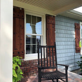 Rustic cedar shutters adorning a house with a front porch and rocking chair