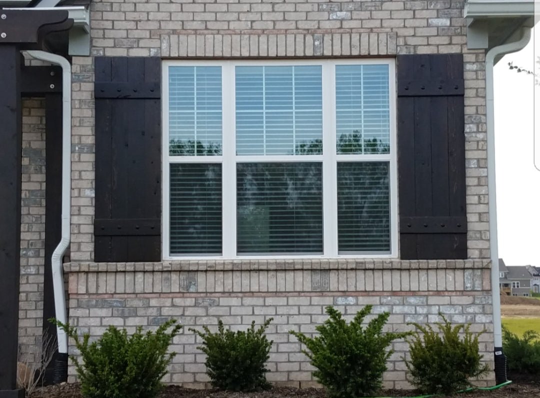 Brick house featuring windows with rustic cedar shutters