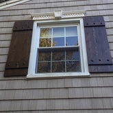 Side view of a house window featuring rustic cedar shutters