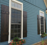 Pair of rustic cedar shutters on a window with floral decor
