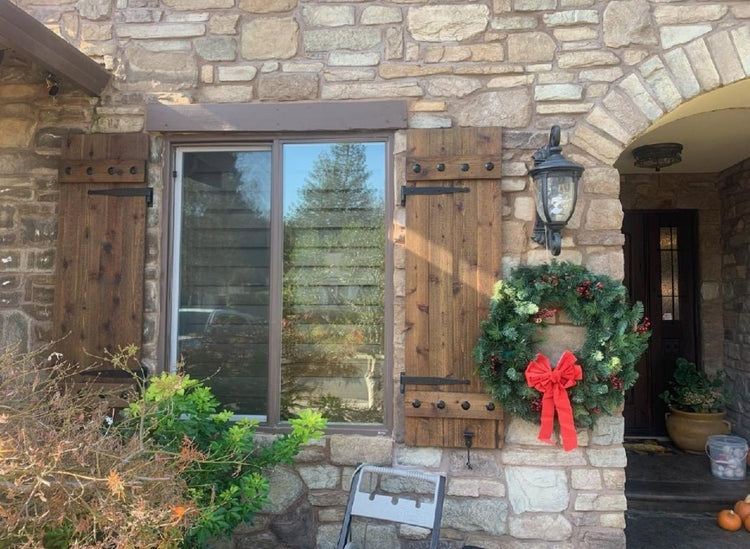 Stone house decorated with rustic cedar shutters and festive wreaths