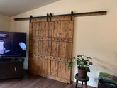 Scene with a television on a wooden floor beside a barn door with Customized Barn Sliding Hardware