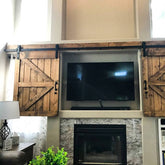 TV mounted above a fireplace, concealed by sliding barn doors