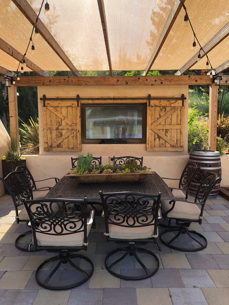 Outdoor patio setting featuring the TV Barn Door Package under a canopy